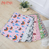 A collection of colorful washable pet training mats for dogs in various patterns and colors laid out on a light wooden floor.
