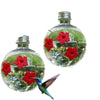 A glass bottle filled with water and green plants, featuring a hummingbird feeding on the flowers.