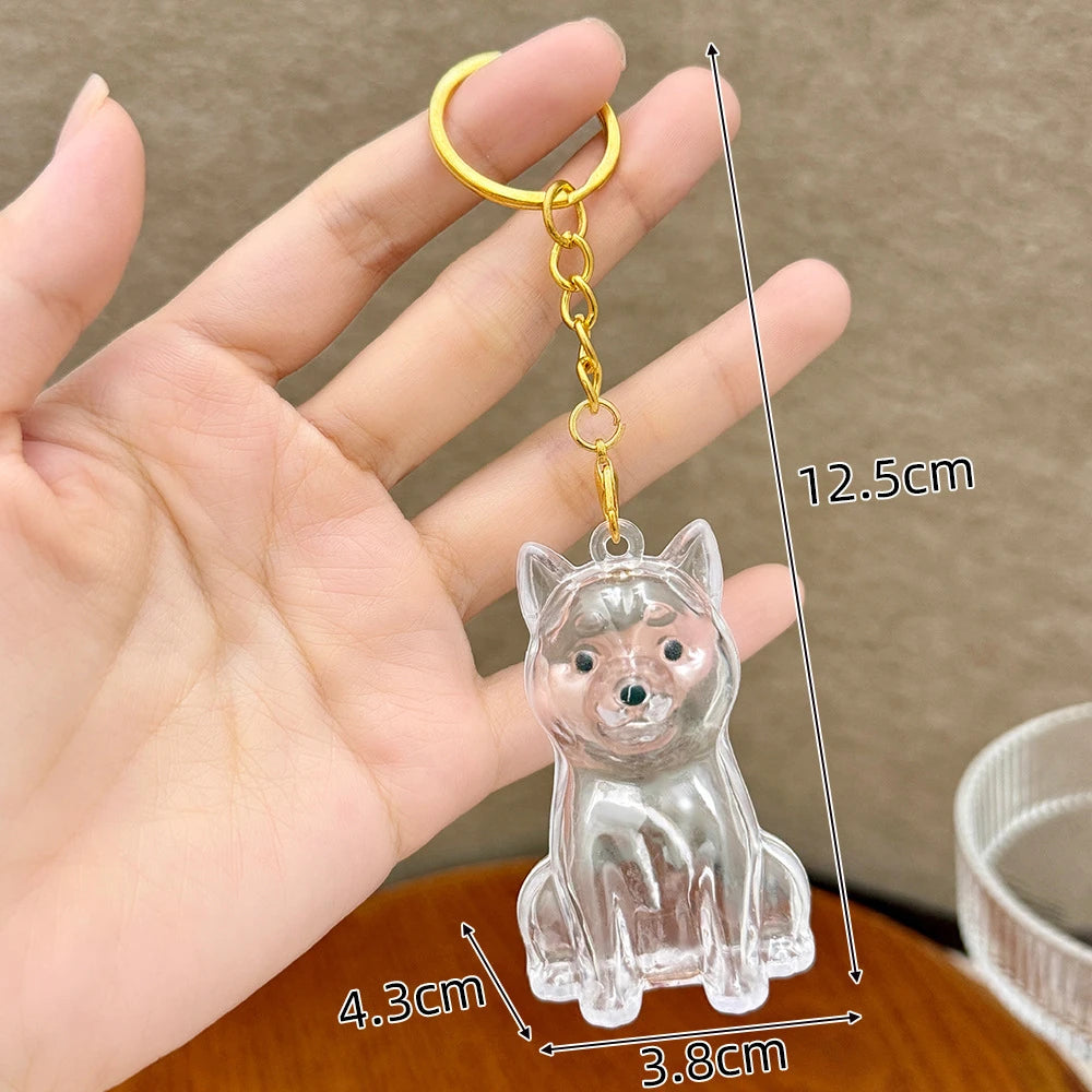 A clear glass puppy-shaped pet hair keepsake keychain with a gold-colored ring and attached to a thin wire.