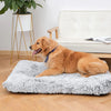 A golden retriever lies on a gray plush pet bed mat next to a white upholstered bench and a gold tripod plant stand.