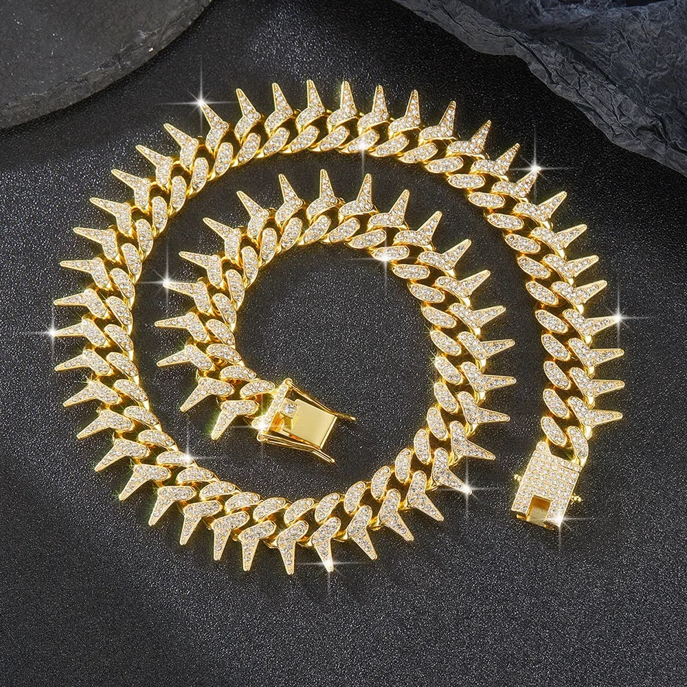 A gold spiked Cuban chain bracelet with diamond accents coiled on a dark surface.