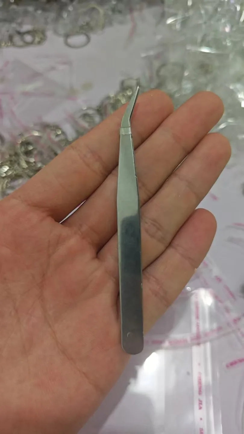 Une main tient un kit de porte-clés pour poils de chien en argent, au design élancé et allongé.