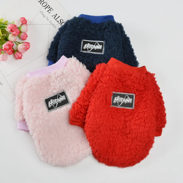 Three cozy fleece dog sweatshirts in navy blue, pink, and red with black labels