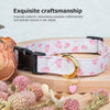 Weiß-rosa gemusterter Baumwollhundehalsband mit goldener Herz- und Erdbeeranhängsel auf Holzoberfläche.