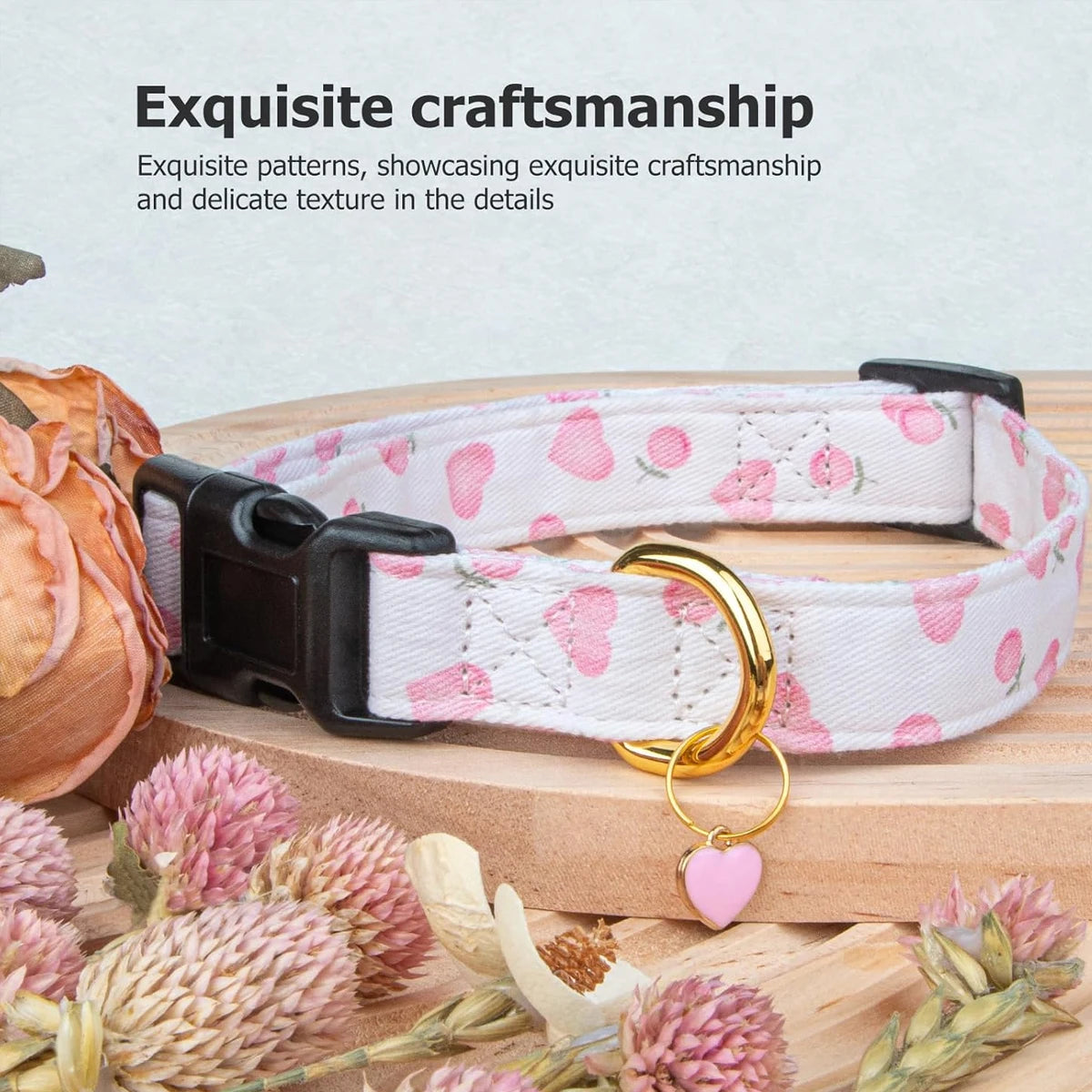 Weiß-rosa gemusterter Baumwollhundehalsband mit goldener Herz- und Erdbeeranhängsel auf Holzoberfläche.
