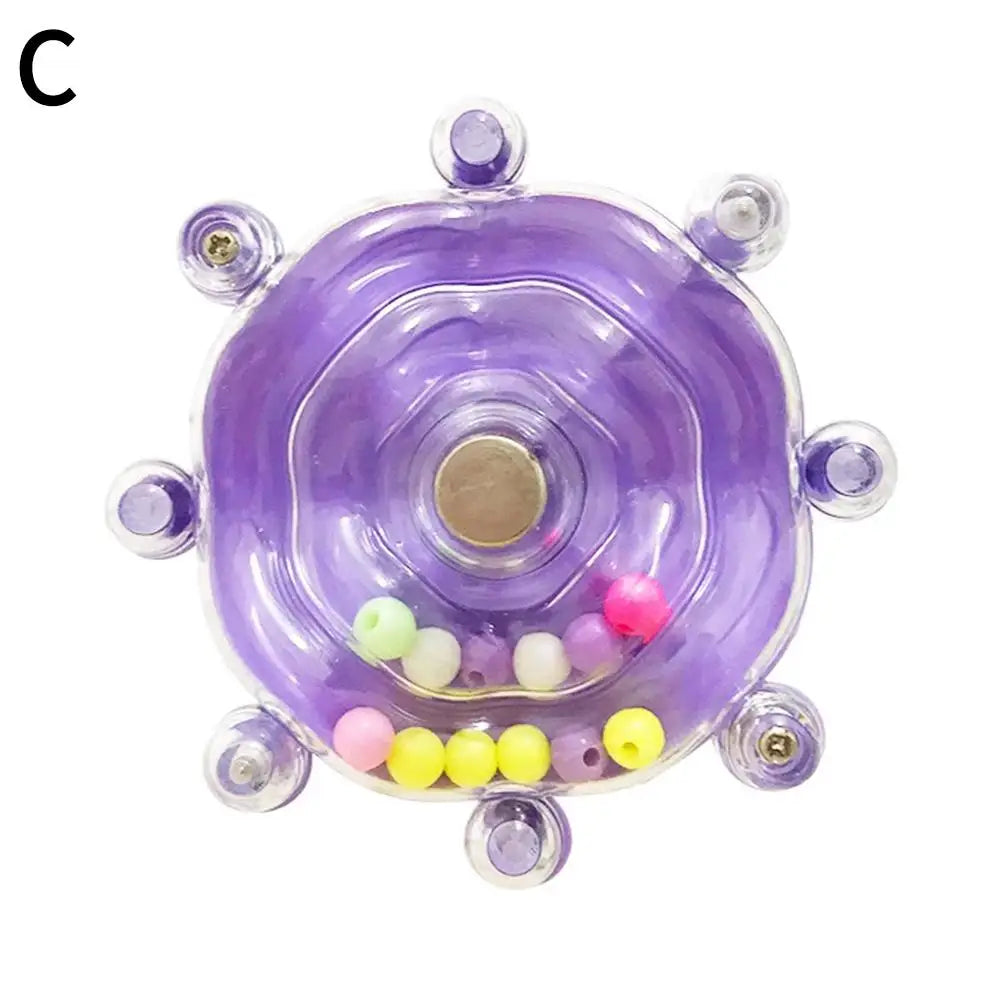 A purple rotating parrot treat dispenser with small colored balls inside.