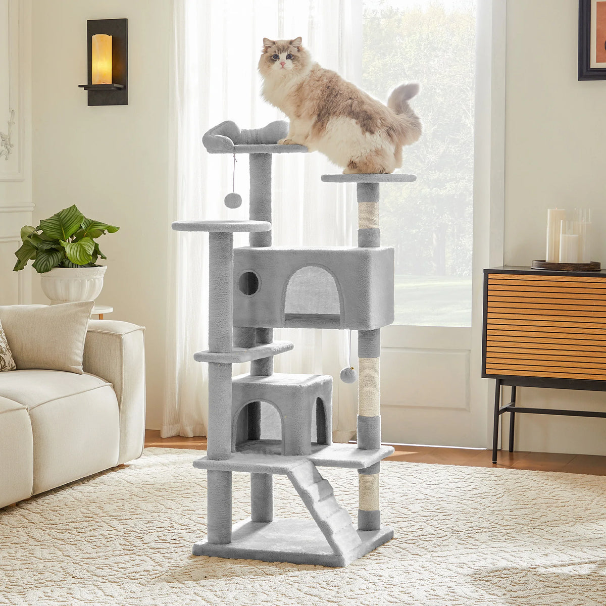 A multi-level gray cat tree with scratching posts and condos stands in a bright room next to a window.