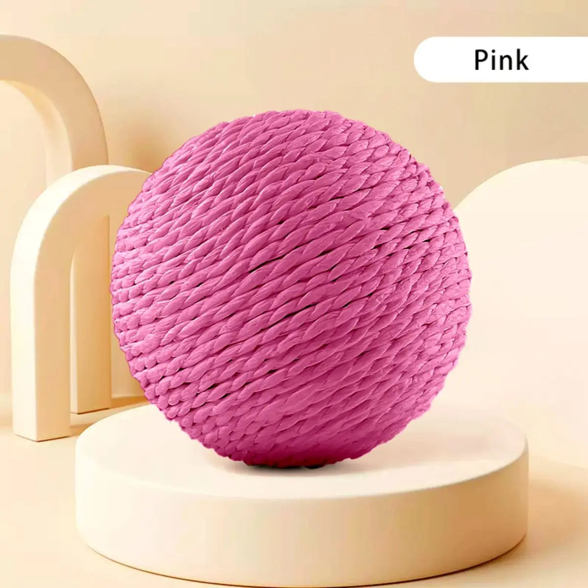 A pink interactive sisal cat scratching ball resting on a white stand.