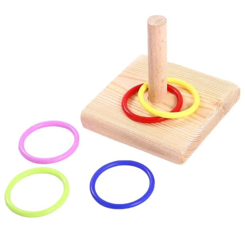 A wooden dowel and plastic rings of various colors are shown on a wooden board.
