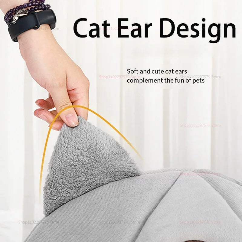 Une main touche une oreille de chat gris et duveteux sur un lit pour animaux en peluche.