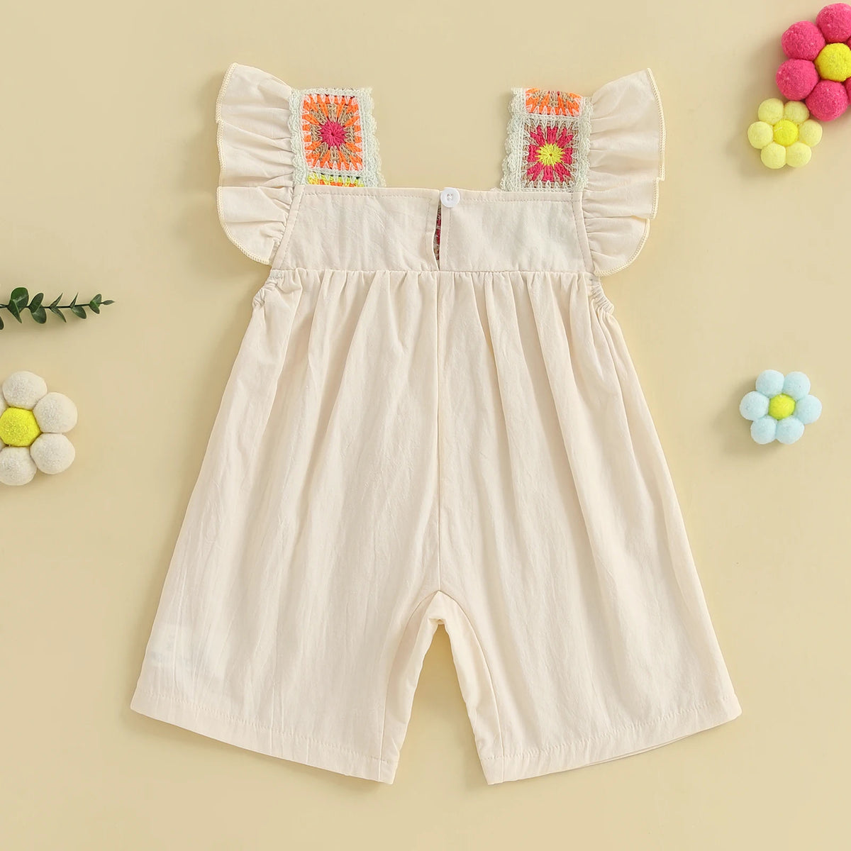 A light pink floral embroidery toddler romper for girls with ruffled trim and yellow and pink flower accents.