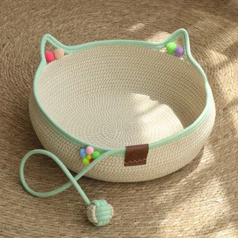 A light green cat scratcher and comfort bed with play balls resting on a tan surface.