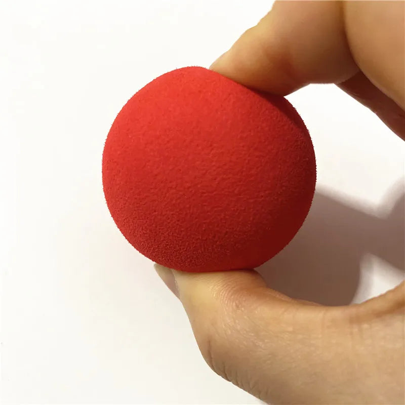 A hand is holding a single red EVA foam practice golf ball, showing its texture and size.