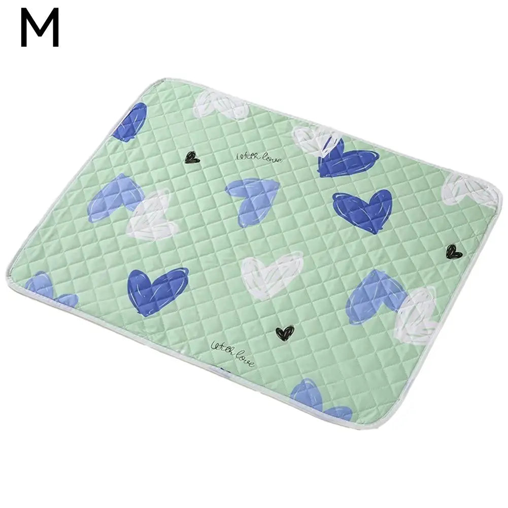 A green quilted pet urine pad featuring blue and white heart shapes for reusable cleaning.
