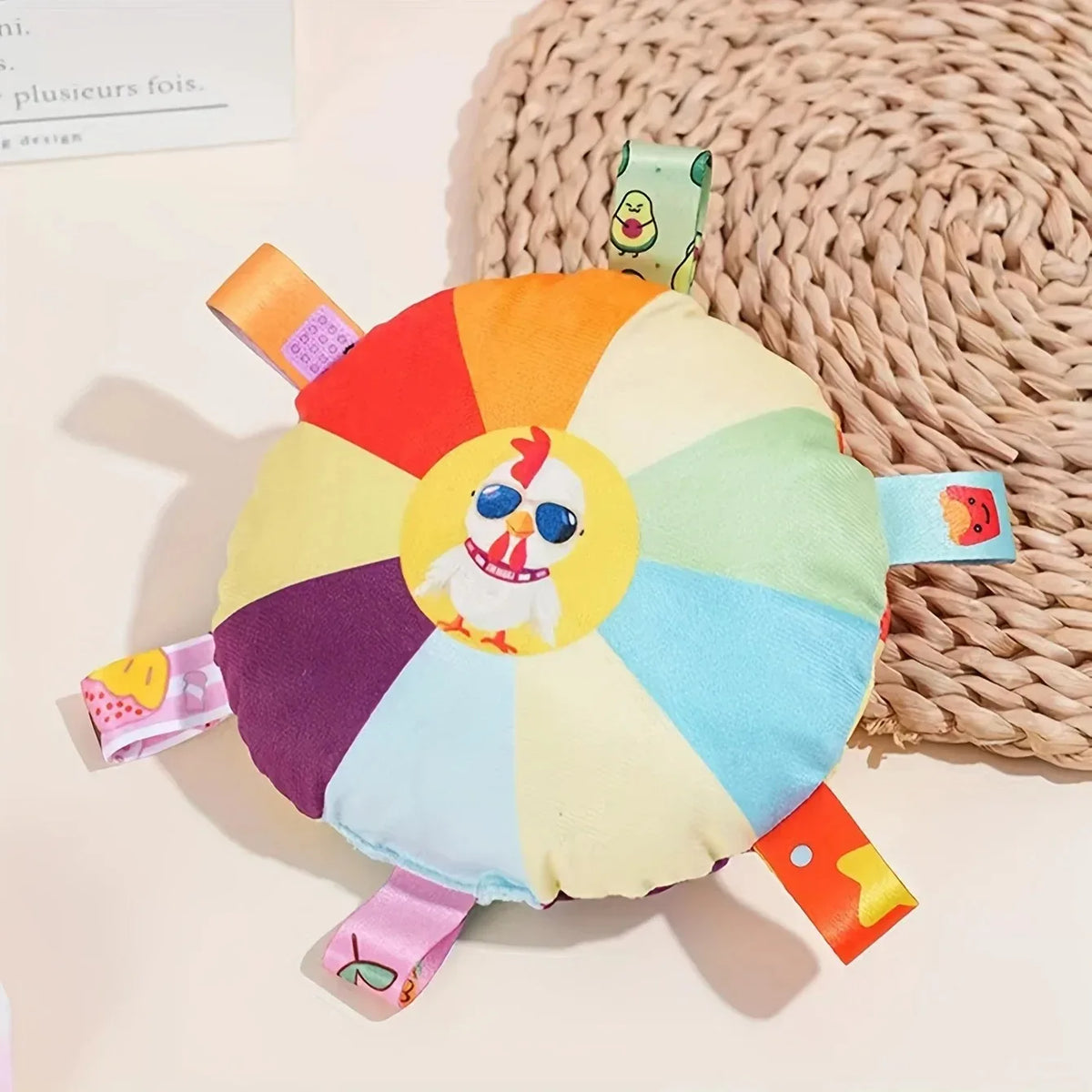 A colorful plush dog toy shaped like a flying disc with various colored segments and an embroidered bird face.