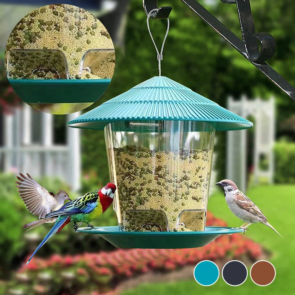A window-mounted bird feeder with a clear viewing panel filled with seeds, hanging from a metal hook.