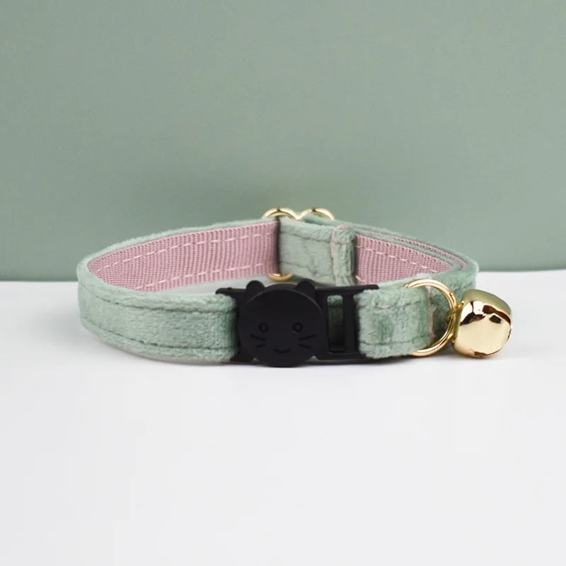 A light green velvet cat collar with a pink lining, black safety buckle, and a gold-colored bowknot.