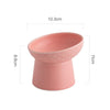 A pink elevated ceramic food bowl for pets, showing its size and shape.