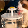 A cat is drinking water from a clear, automatic recirculating water dispenser with a filter.