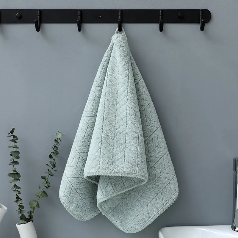A light mint green plush microfiber bath towel hanging on a black rack.