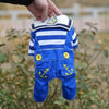 A blue and white striped seaman dog costume jumpsuit being held by a hand outdoors.