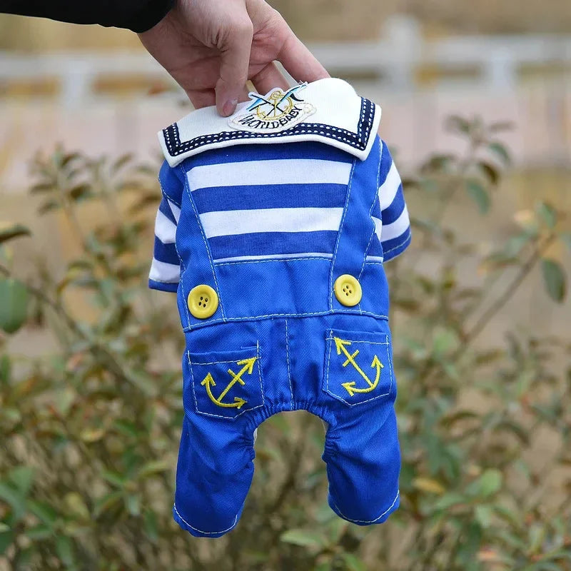 A blue and white striped seaman dog costume jumpsuit being held by a hand outdoors.