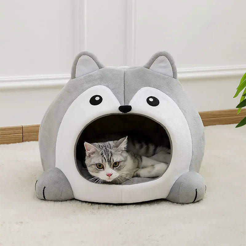 Un lit pour chat en peluche gris avec une entrée pour un petit chaton tigré.