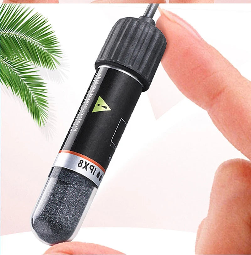 A black USB mini aquarium heater with a silver tip is held by a hand, next to a green palm leaf.