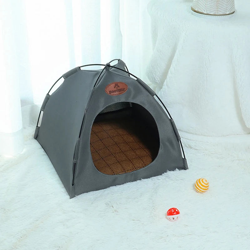 A gray foldable outdoor cat tent with an entrance, resting on a white fluffy surface.