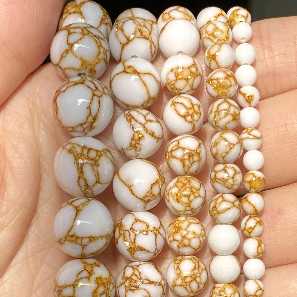 A collection of natural stone beads in white and amber marbled patterns arranged in a linear display.