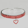 A silver collar adorned with red and white rhinestones, featuring a heart pendant.