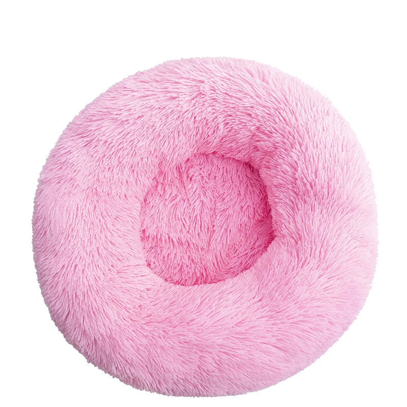 A round, pink plush pet bed designed for dogs and cats.