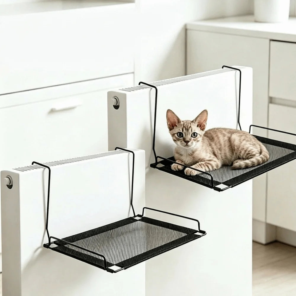 A tabby kitten is resting in a black mesh hammock mounted on a white cabinet door.