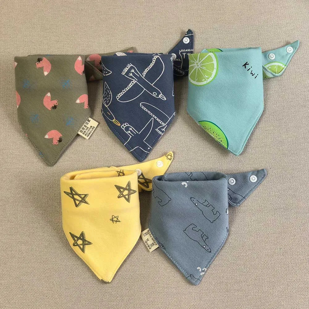 A set of five cotton triangle baby bibs featuring various cartoon prints including a kiwi and a dinosaur.