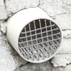 A round stainless steel roof and floor drain mesh cover set against a rough stone wall.