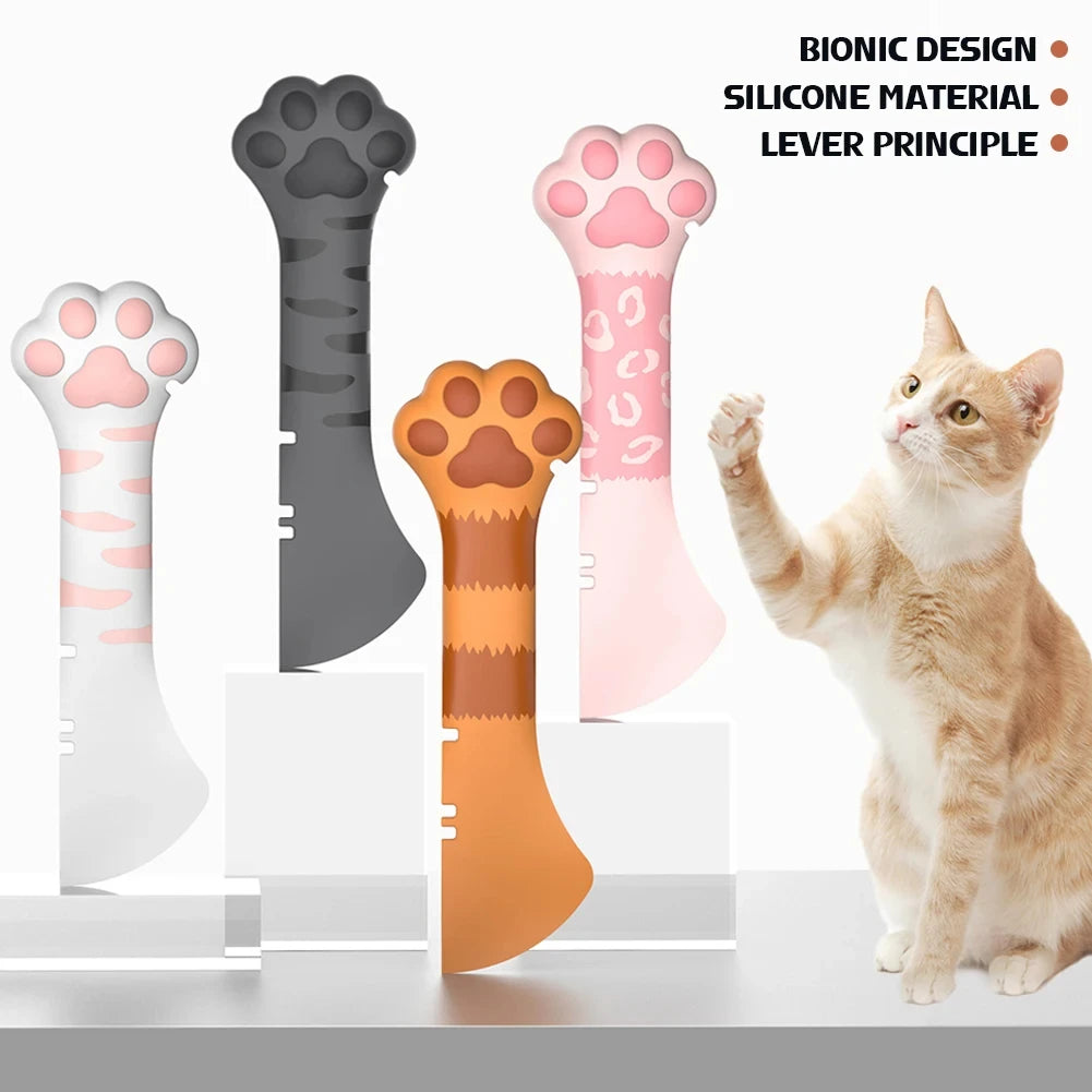 A cat is using a silicone paw tool designed as a can opener or food scoop for pets.