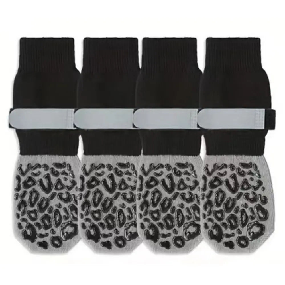 A pack of four black anti-slip cotton dog socks with adjustable grip and leopard print bottoms.
