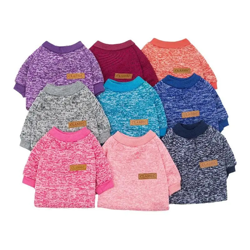 A collection of nine knitted sweaters or jackets in various shades of purple, pink, orange, and blue for small dogs.
