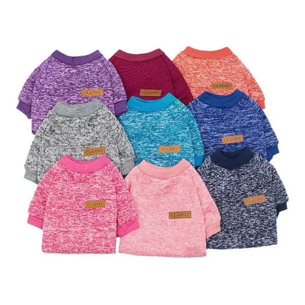 A collection of nine knitted sweaters or jackets in various shades of purple, pink, orange, and blue for small dogs.