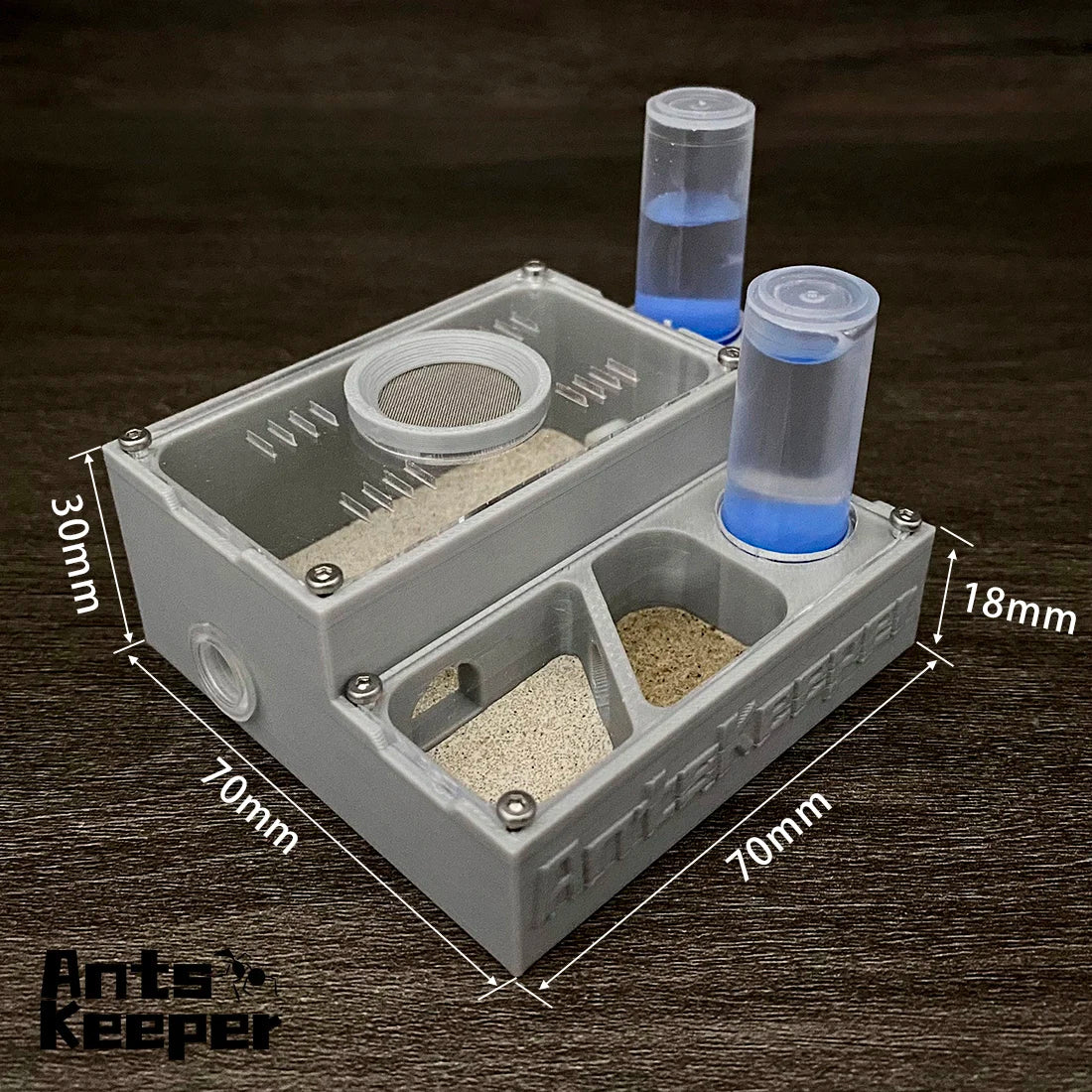 A compact white ant keeper box with two compartments and water feeders filled with blue liquid.