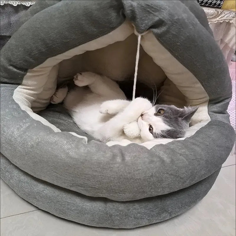 A gray plush cat nest bed with a hood, inside of which a gray and white cat is resting.
