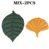 Two reversible leaf-print pet cushions, one dark green and one orange, with quilted texture.