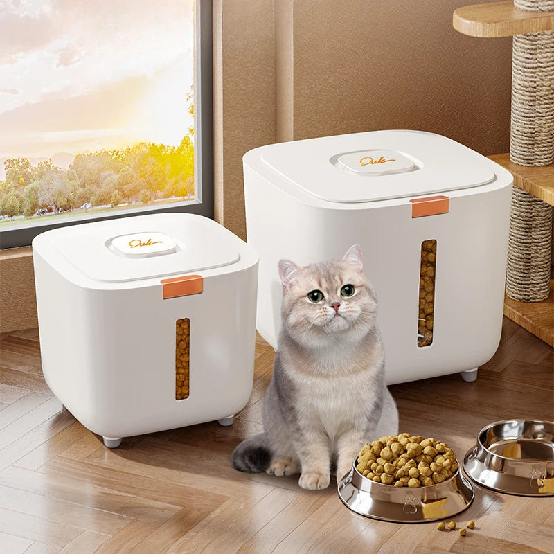 A white airtight pet food storage bucket sits on a wooden surface with dry pet food and a metal bowl nearby.