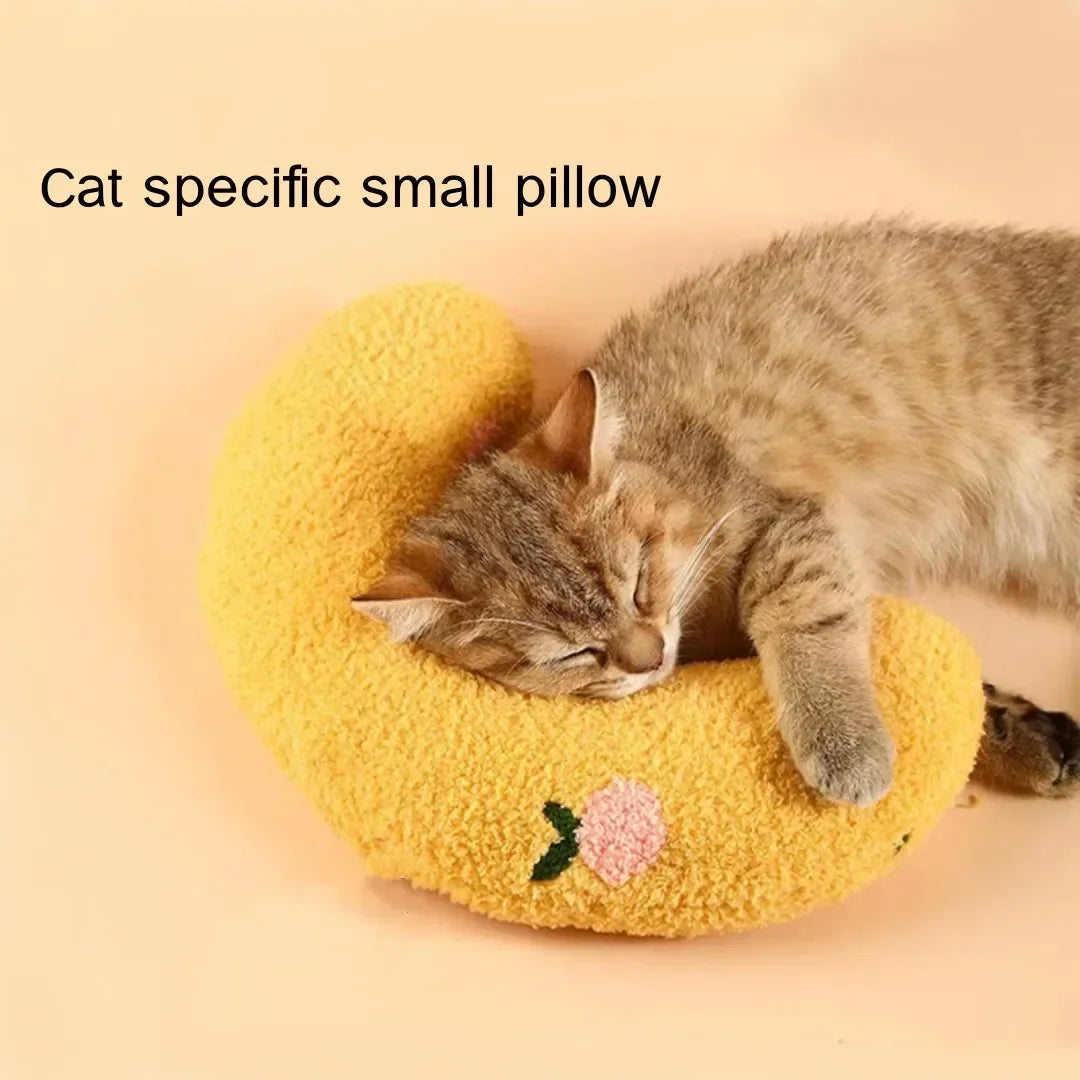 A tabby cat is sleeping inside a yellow U-shaped pillow designed for cats.