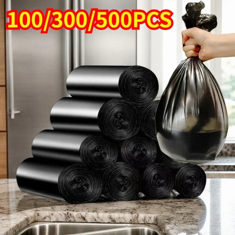 A stack of black disposable plastic garbage bags with tie handles is being held by a hand.