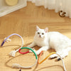 Three colorful organic cotton cat chewing ropes with tassels lying on a wooden floor.