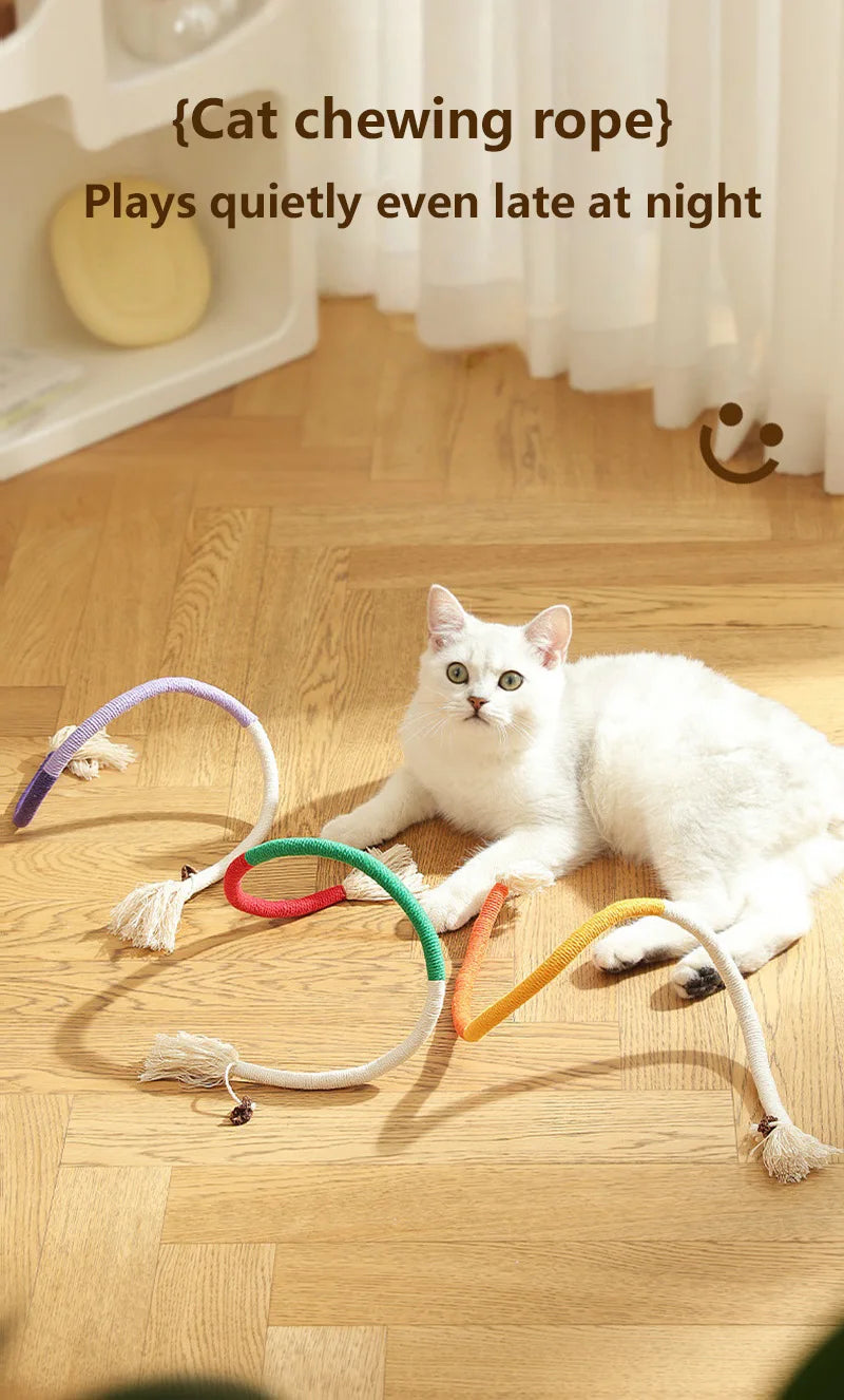Three colorful organic cotton cat chewing ropes with tassels lying on a wooden floor.