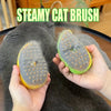 A hand holds a green and yellow steamy cat brush against a gray cat's fur.