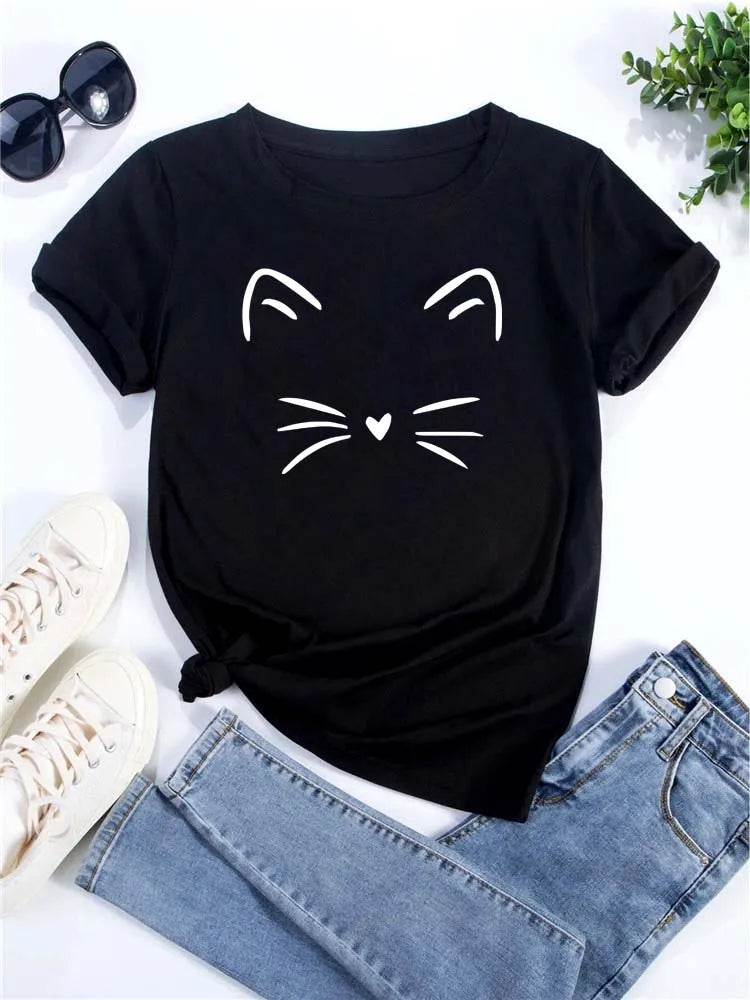 Camiseta negra de manga corta con diseño de cara de gato blanco, junto a gafas de sol y jeans.