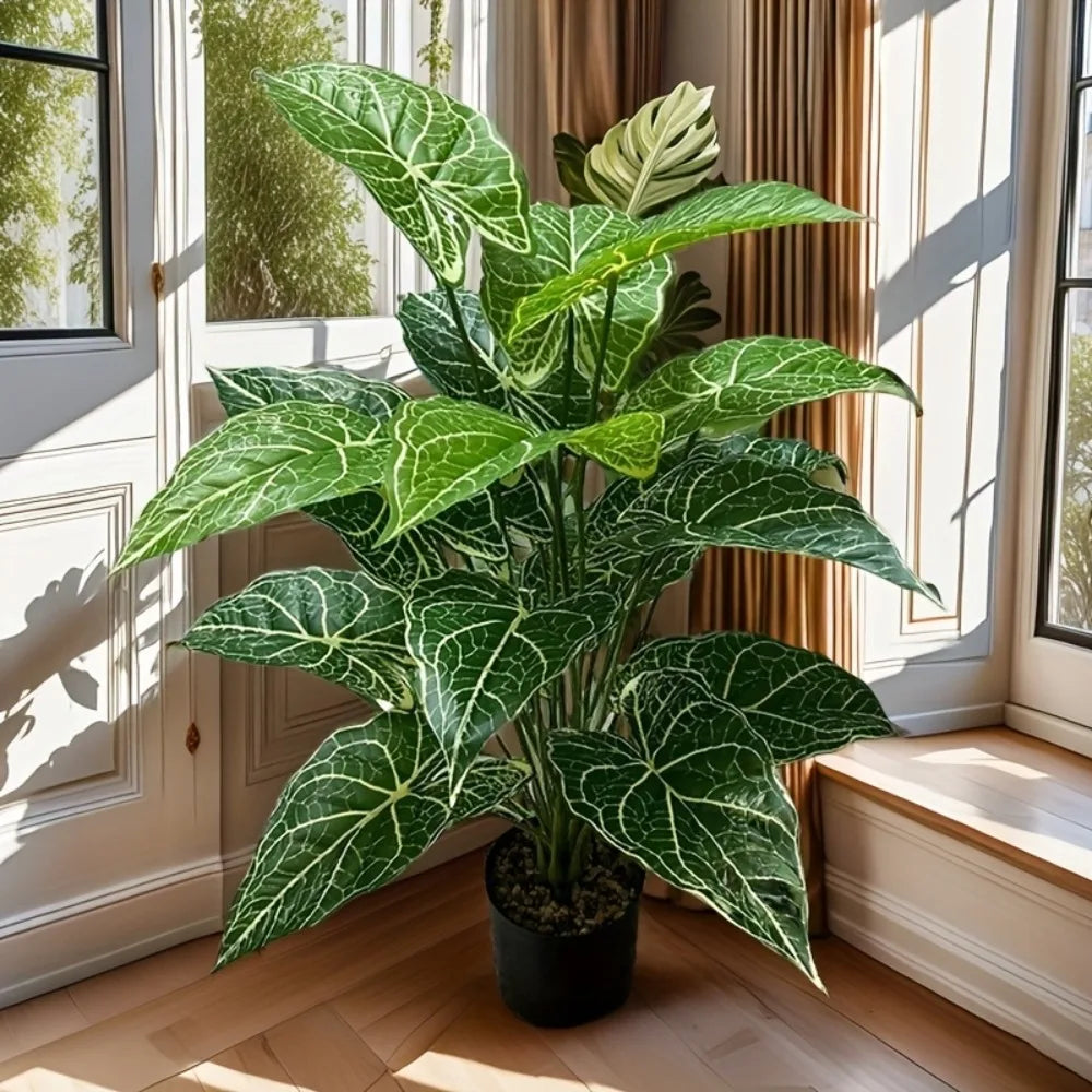 A large artificial Monstera plant with green leaves is displayed indoors next to a window.